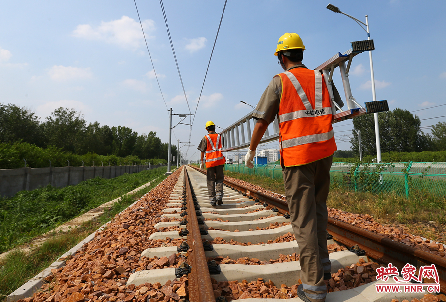 滾燙的鐵軌上，兩個扛著梯子的檢修員走向第四個檢修點(diǎn)