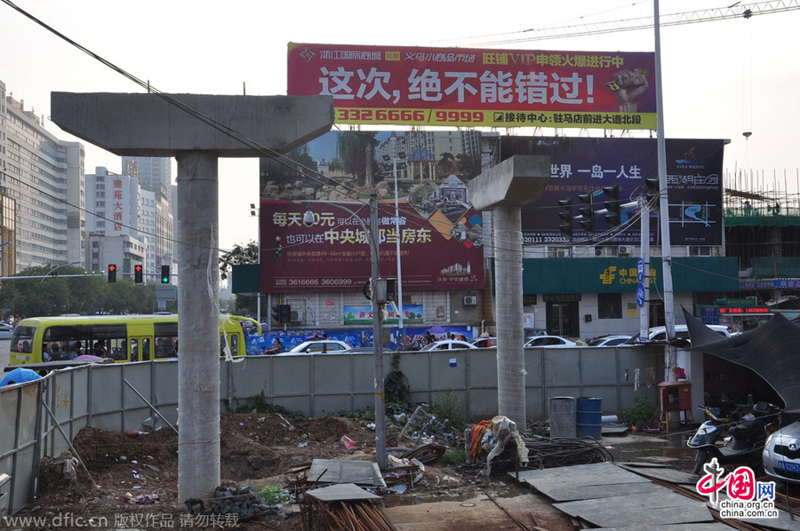 過街天橋一側(cè)的橋樁早已打好,可是對面的郵政銀行網(wǎng)點依舊在照常營業(yè)。