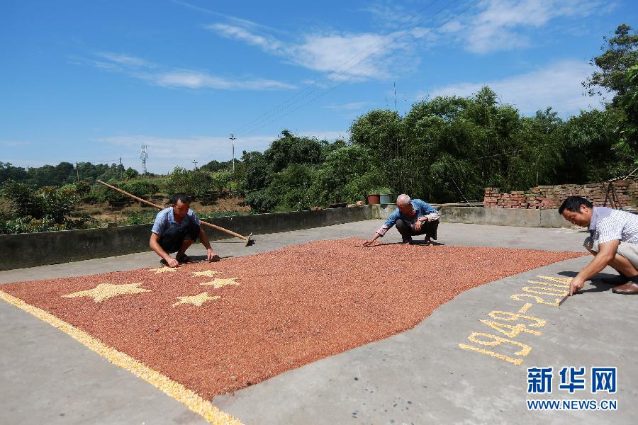 村民馬玉明（左一）用豐收的高粱和玉米在院壩里擺國旗為祖國慶生。