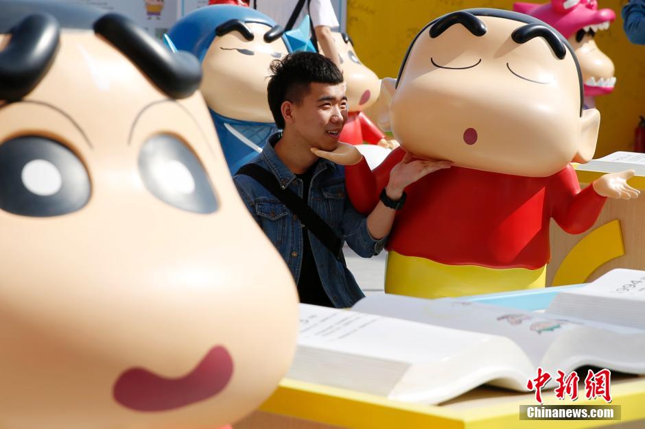 4月22日，游客與蠟筆小新合影?！跋灩P小新25周年紀(jì)念特展”日前在北京開展，吸引了不少市民游客。