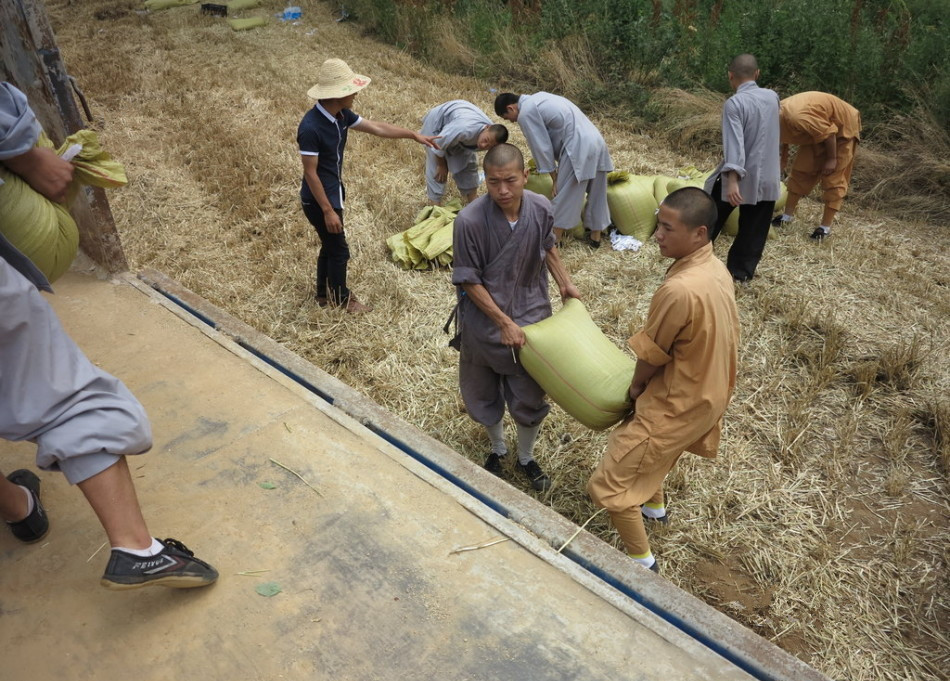 武僧將打包后的糧食集中至運輸車輛上。