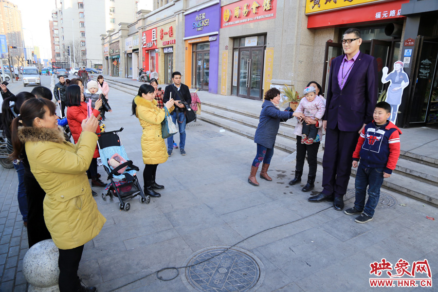 過路市民爭相與“巨人”合影。