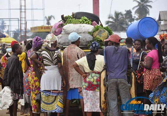 當(dāng)?shù)貢r(shí)間2014年8月14日，利比里亞蒙羅維亞，市場(chǎng)里的商人們圍著一輛汽車。