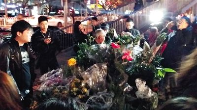 昨晚7時許，三里屯太古里西邊附近一過街天橋旁邊，聞訊而至的網友圍住了賣花老人，爭相買花。 網友“行者橙子”供圖