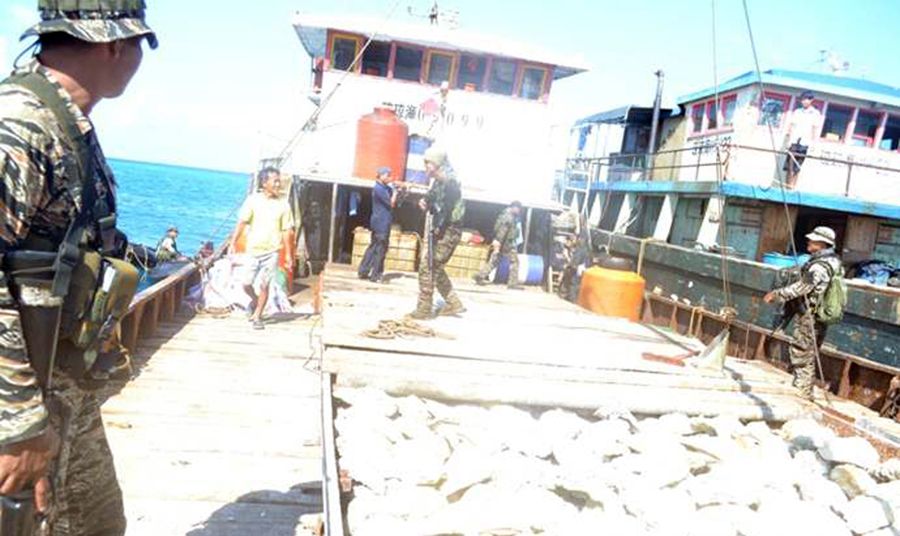圖為菲律賓海軍持槍檢查中國漁民的照片。