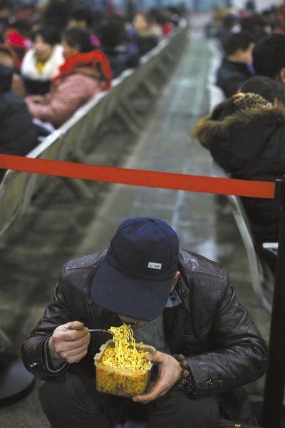 北京西站臨時候車廳，鄧軍吃著妻子泡好的方便面