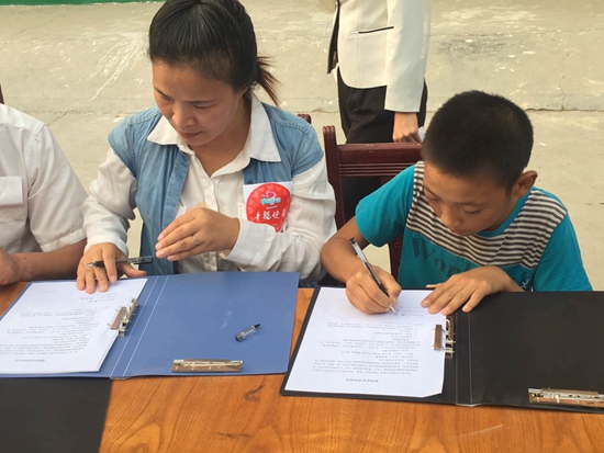 赤腳“小電工”張闖與結(jié)對幫扶的幸福使者代表在簽幫扶協(xié)議 攝影 張麗